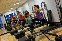 Photo of a personal trainer assisting clients in a pilates machine class