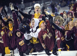 Photo of high school sports fans, decked in team apparel, cheering from the stands