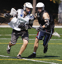 Photo of Lacrosse players chasing the ball on a synthetic turf field