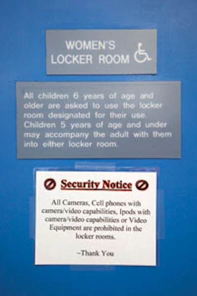 Photo of a security notice posted on a women's locker room door warning that all camera/video equipment is prohibited