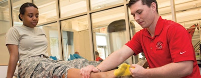 A UCM athletic trainer checks for lower-extremity injuries common to cadets completing endurance training in heavy boots. [Photo by Bryan Tebbenkamp, UCM photographer]