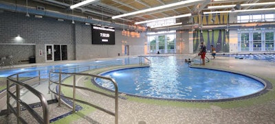 The UNCG activity pool integrates a lounging area, basketball hoop and vortex for users to relax. Movies are often shown on the large video screen viewed easily from the activity pool lounging benches. (Photo courtesy Aquatic Design Group)