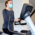 A woman in a facemask jogs on a Matrix treadmill
