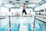 Boy jumping off a diving board into an indoor pool