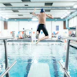 Boy jumping off a diving board into an indoor pool