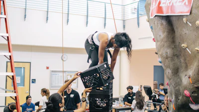 Protected by a climbing wall’s belay system, a Cal State Bakersfield student balances atop a crate stack as the tower grows taller.