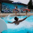 Two lifeguards watch over swimmers at the Douglass Park pool in June 2022 in Indianapolis, which suffered a lifeguard shortage last year. Many states and cities suffering similar shortages have made major changes in how they train, recruit and compensate lifeguards.