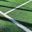 White boundary lines crossing on vibrant green artificial sports field surface
