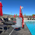 Accessible pool lift device by swimming pool with lounge chairs and mountain view