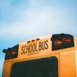 Yellow school bus with emergency exit against bright blue sky