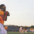 Quarterback in yellow jersey ready to throw football at sunset on football field