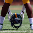 Football helmet resting on grass field between player's legs