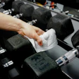 Hand cleaning black dumbbell with white towel in gym weight room