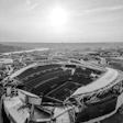 Aerial black and white view of a large football stadium with surrounding urban landscape