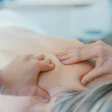 Hands performing therapeutic massage on shoulder or back