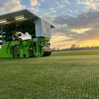 Green autonomous farming robot working in crop field at golden sunset
