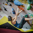 Rock climber scaling colorful indoor bouldering wall with dynamic climbing pose