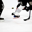 Hockey players' skates and hockey sticks battling for puck on ice
