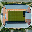 Aerial view of soccer stadium with orange seats and green playing field in urban setting