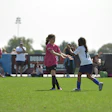 Young girls playing soccer on green field during Dubai sports tournament