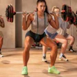 Group fitness class doing synchronized squats in a gym studio