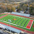 Aerial view of a high school football stadium with red track and green field