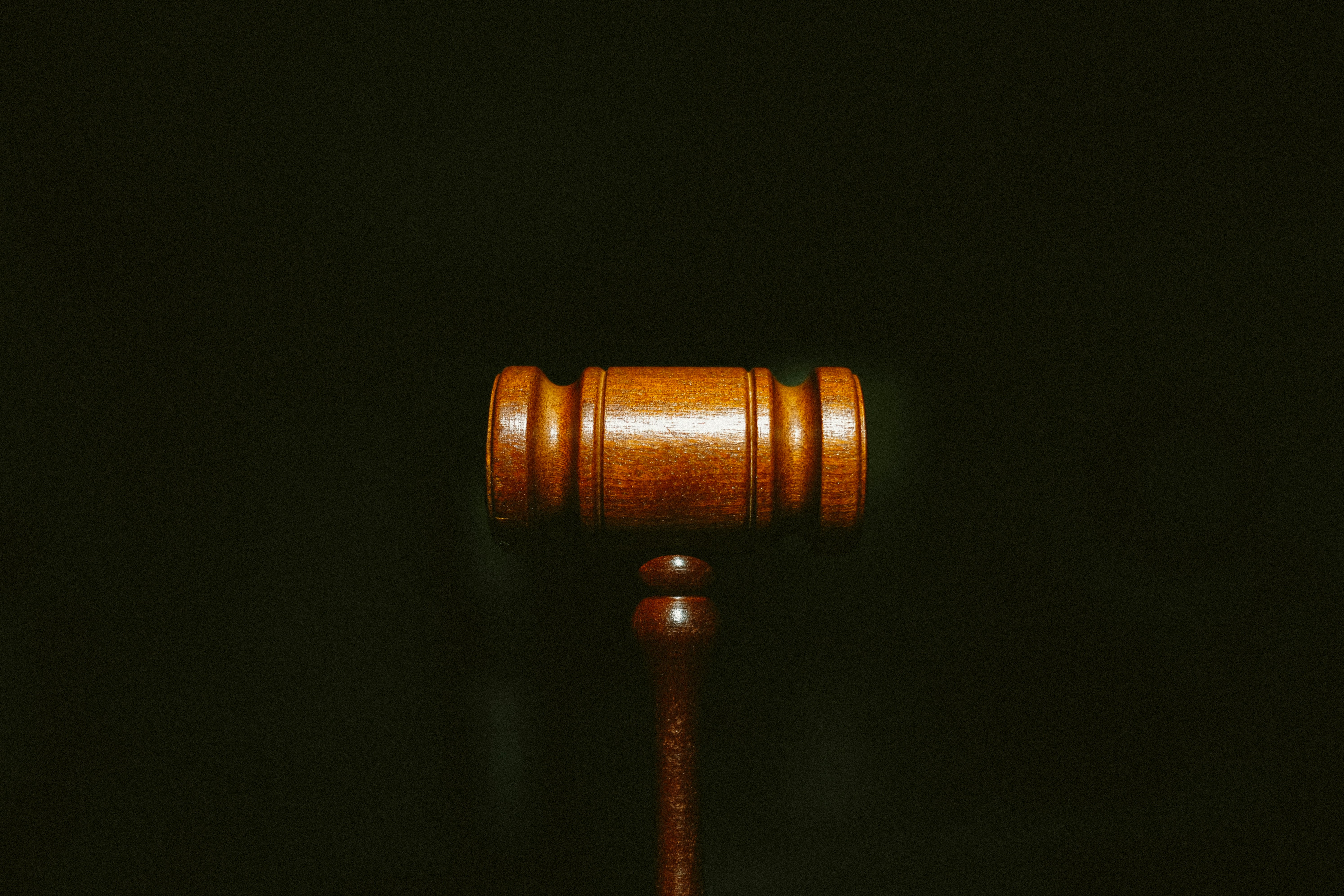 Wooden gavel on dark background, illuminated with warm amber tones