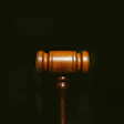 Wooden gavel on dark background, illuminated with warm amber tones