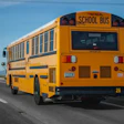 Yellow school bus driving on highway with mountains in background