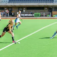 Field hockey players competing on green turf during a match