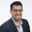 Smiling professional wearing glasses and navy blazer with checkered shirt