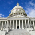 US Capitol building with white columns and dome against blue sky with clouds
