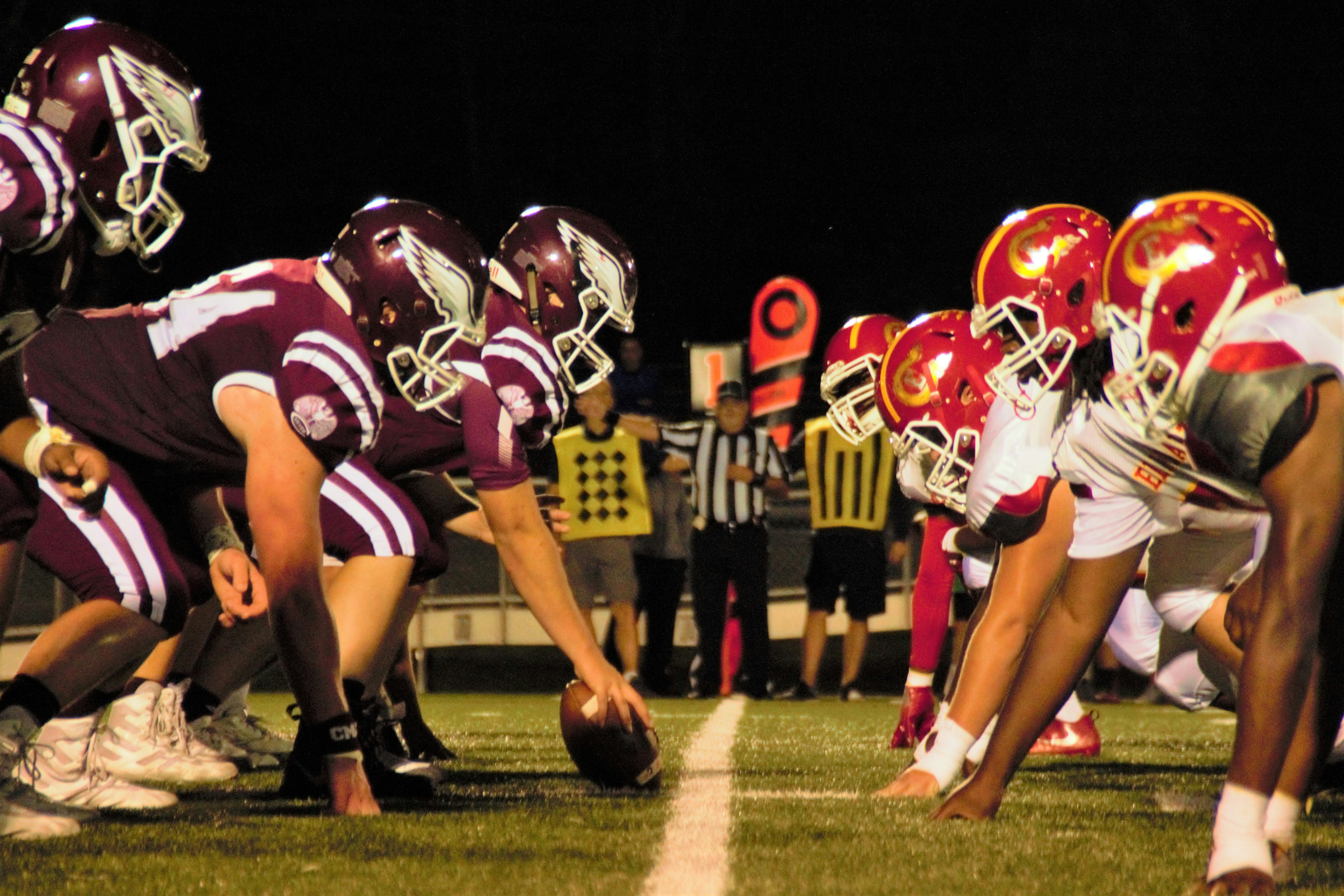 Football teams facing off at line of scrimmage during night game