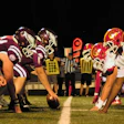 Football teams facing off at line of scrimmage during night game