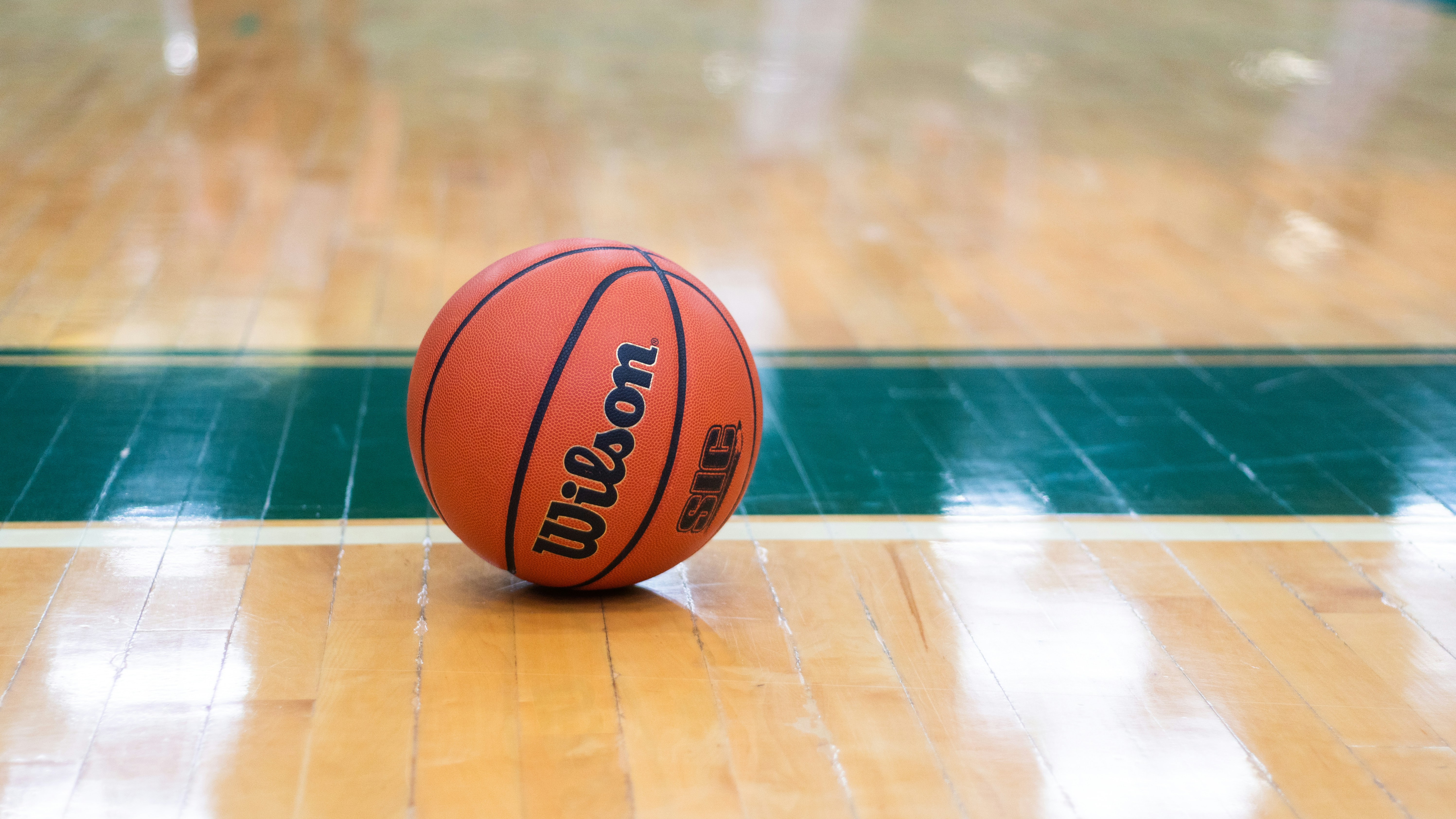 Orange Wilson basketball resting on wooden gymnasium floor