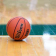 Orange Wilson basketball resting on wooden gymnasium floor