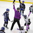 Youth hockey referee signaling during a game with players on ice
