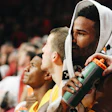 Basketball players on sideline during game, wearing team colors and hoodies