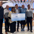 Fluidra team presenting oversized check at corporate event with multiple employees