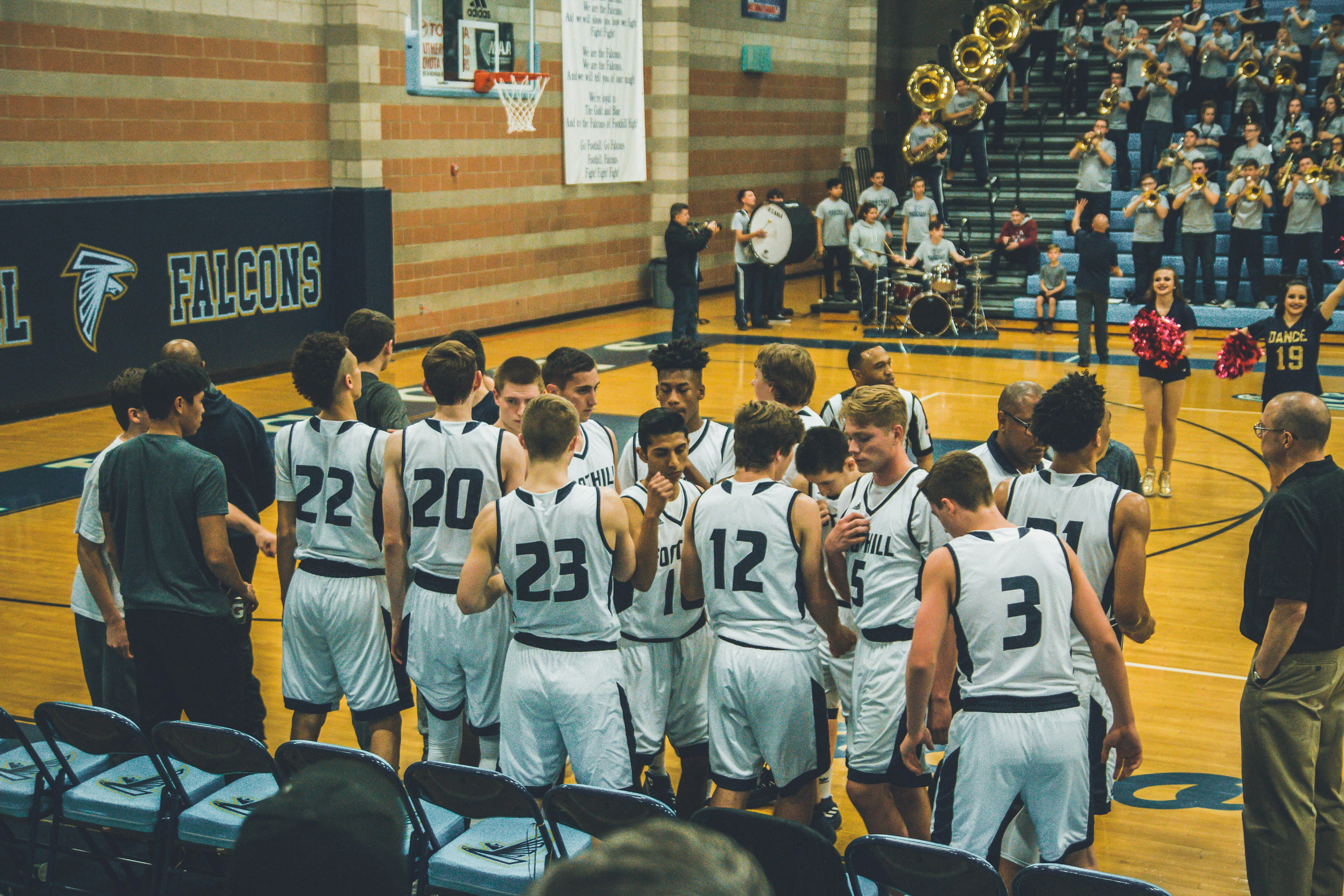 High school basketball team huddled together in gymnasium with Falcons logo