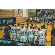 High school basketball team huddled together in gymnasium with Falcons logo