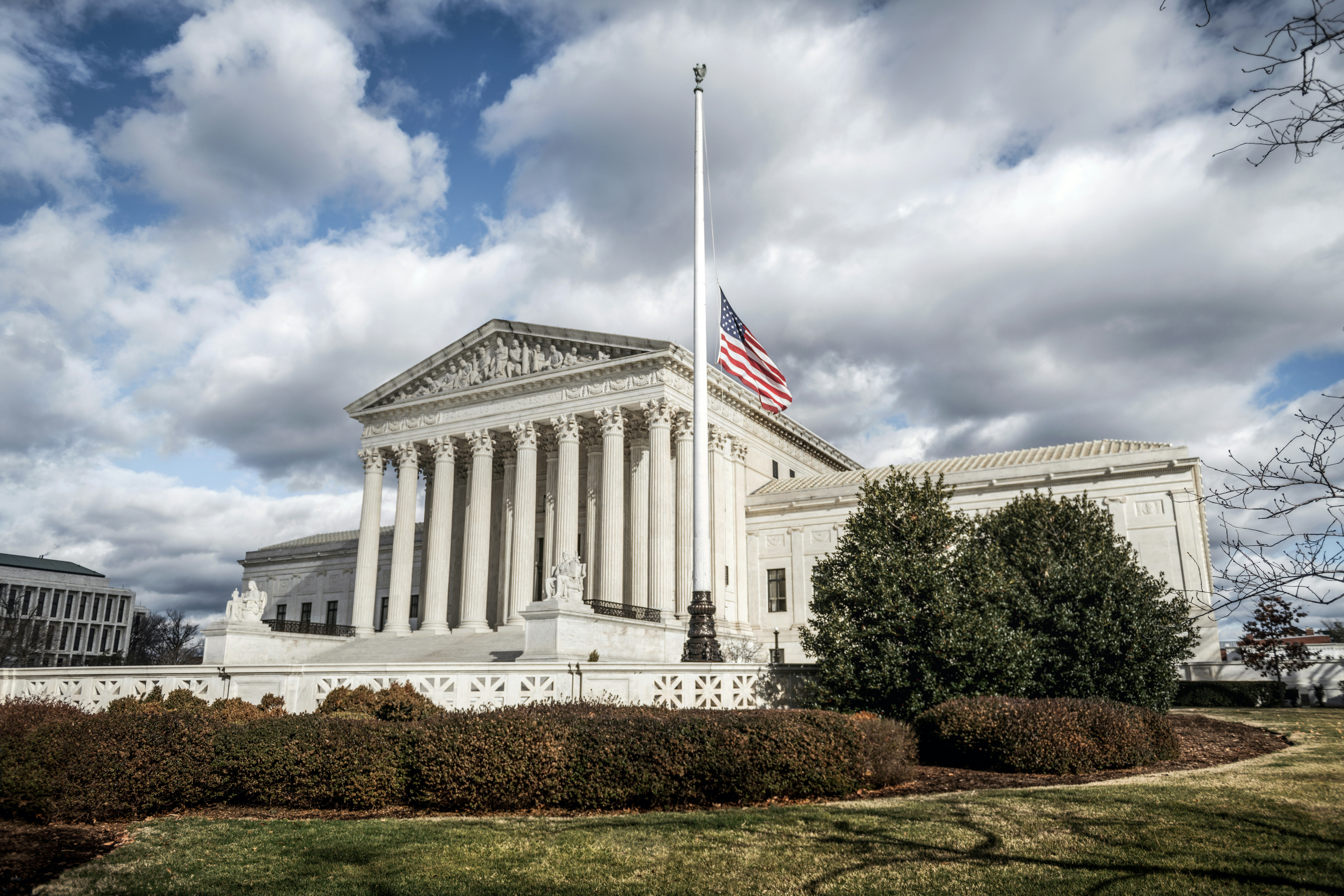 United States Supreme Court building with American flag on cloudy day