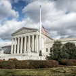 United States Supreme Court building with American flag on cloudy day