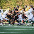 Football players colliding during intense game play on green field