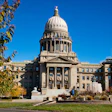 Idaho State Capitol building with white dome, columns, and autumn trees under blue sky