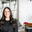 Smiling professional woman in black top standing in bright modern office