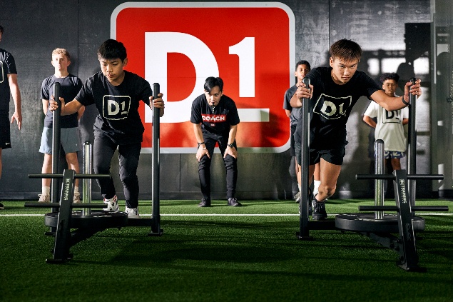 D1 fitness training group performing strength exercises on green turf