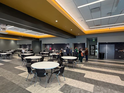 A large meeting room that is divisible into up to three rooms, each with double doors leading to large storage rooms.