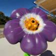 Purple sculptural flower with fuzzy white and yellow center against blue sky
