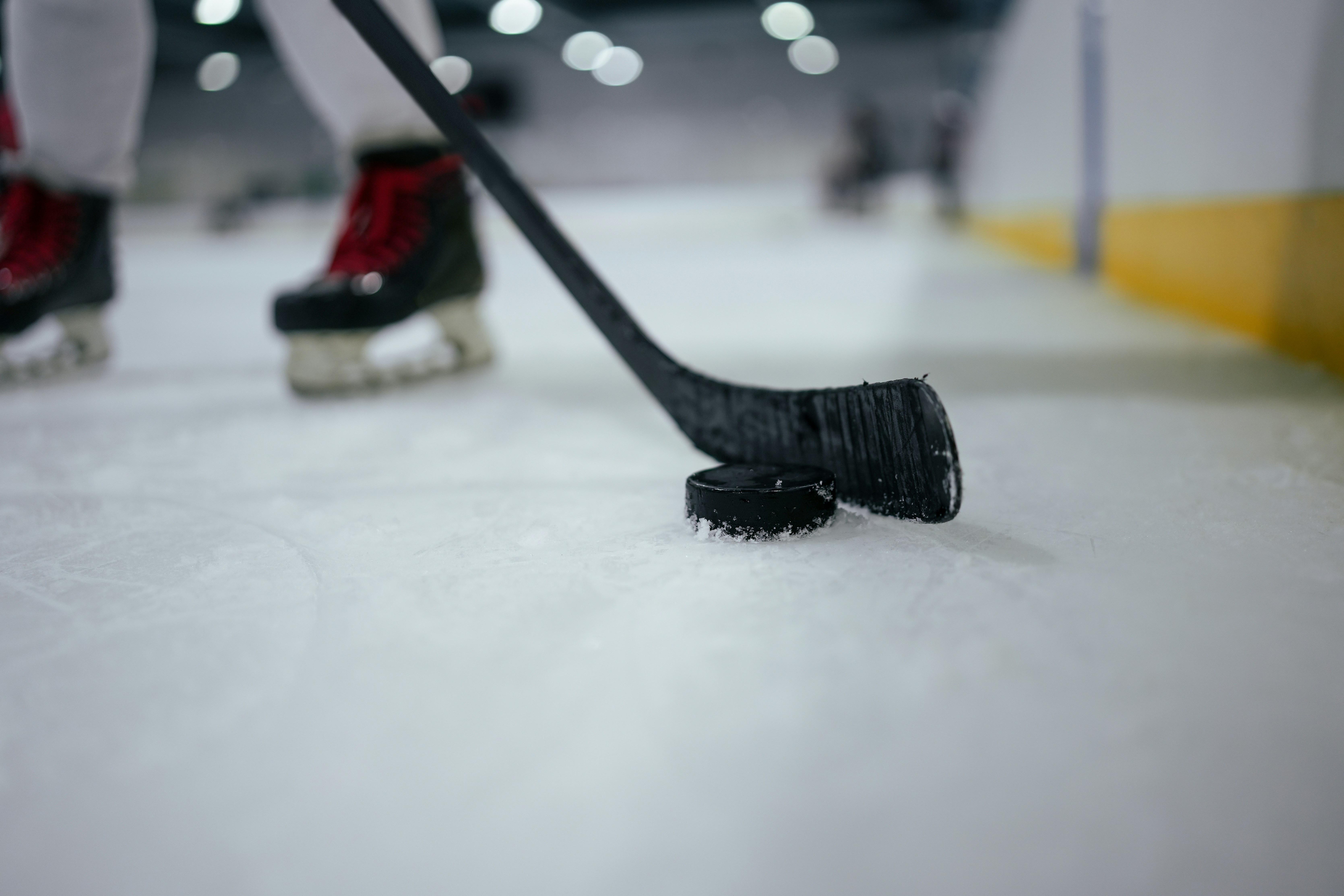 Hockey stick blade touching black puck on ice rink surface
